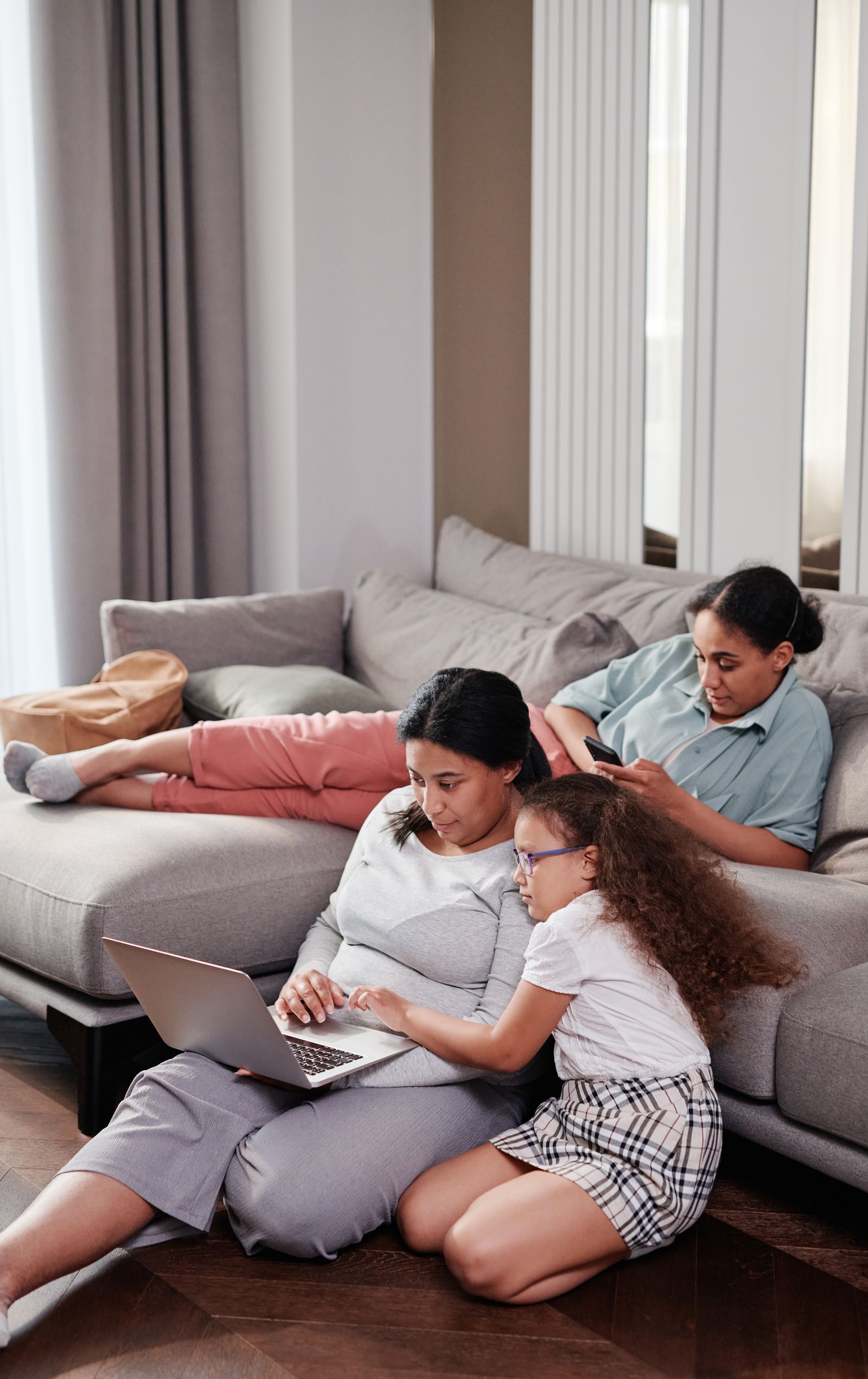 A family together at home, one on a laptop and one on a phone